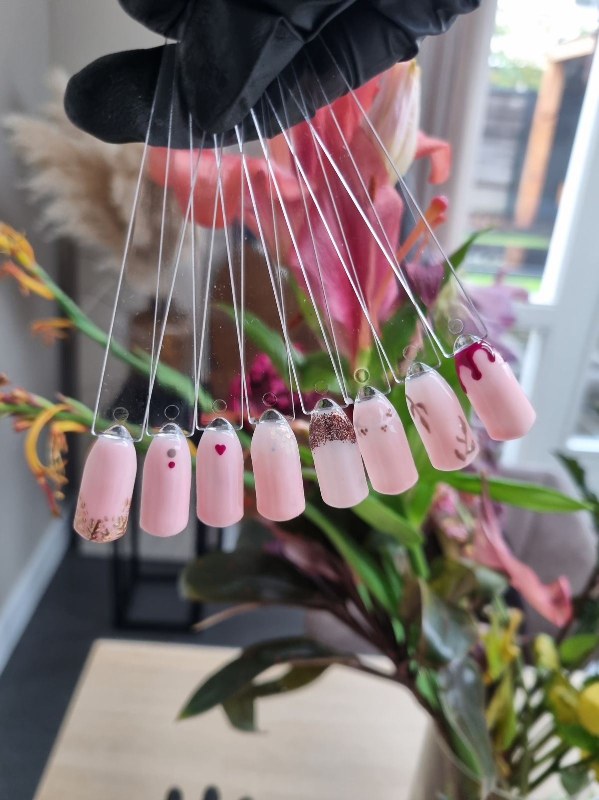 Waaier van nail art staaltjes met hartjes, goud en drip-effect